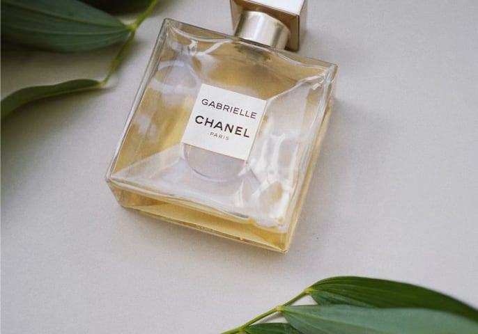 Bottle of Gabrielle perfume near some plants